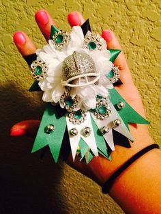 a woman's hand holding a ring with green and white flowers on it, surrounded by jewels