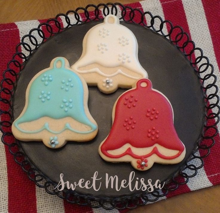 three decorated cookies sitting on top of a black plate next to a red and white striped napkin