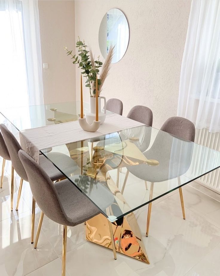 a glass dining table surrounded by grey chairs