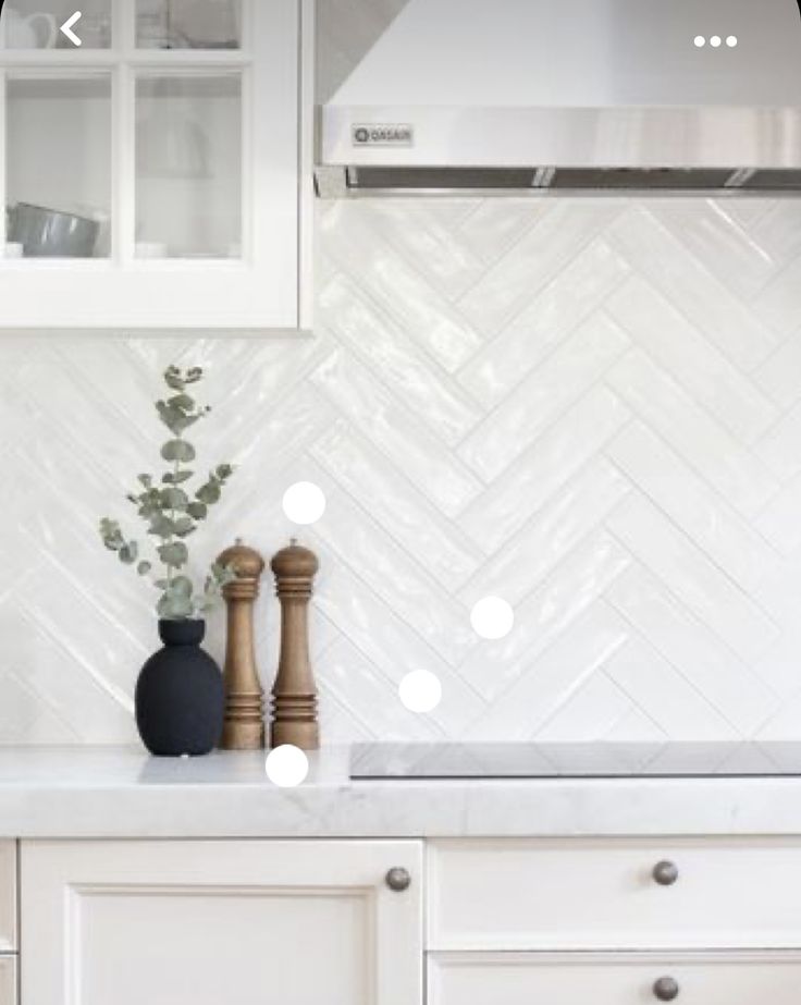 a kitchen with white cabinets and marble counter tops, an oven hood over the stove