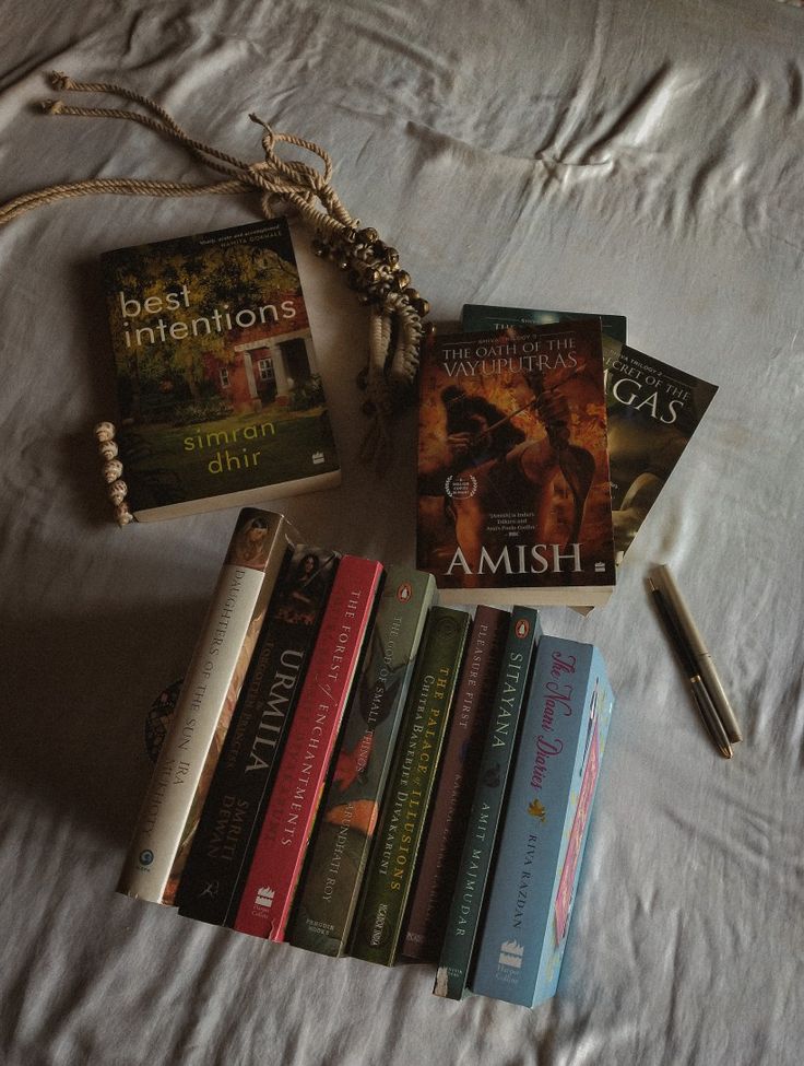 a bunch of books sitting on top of a bed next to a pen and book bag