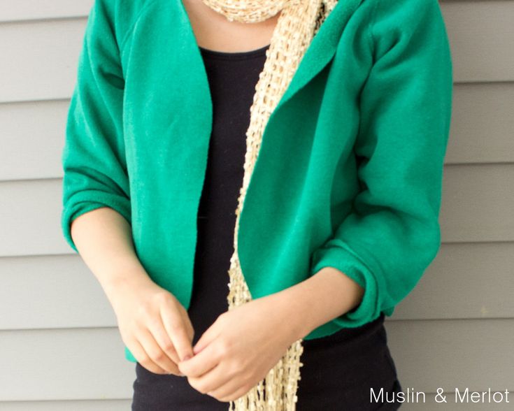 a woman wearing a green jacket and black shirt holding a cell phone in her hand