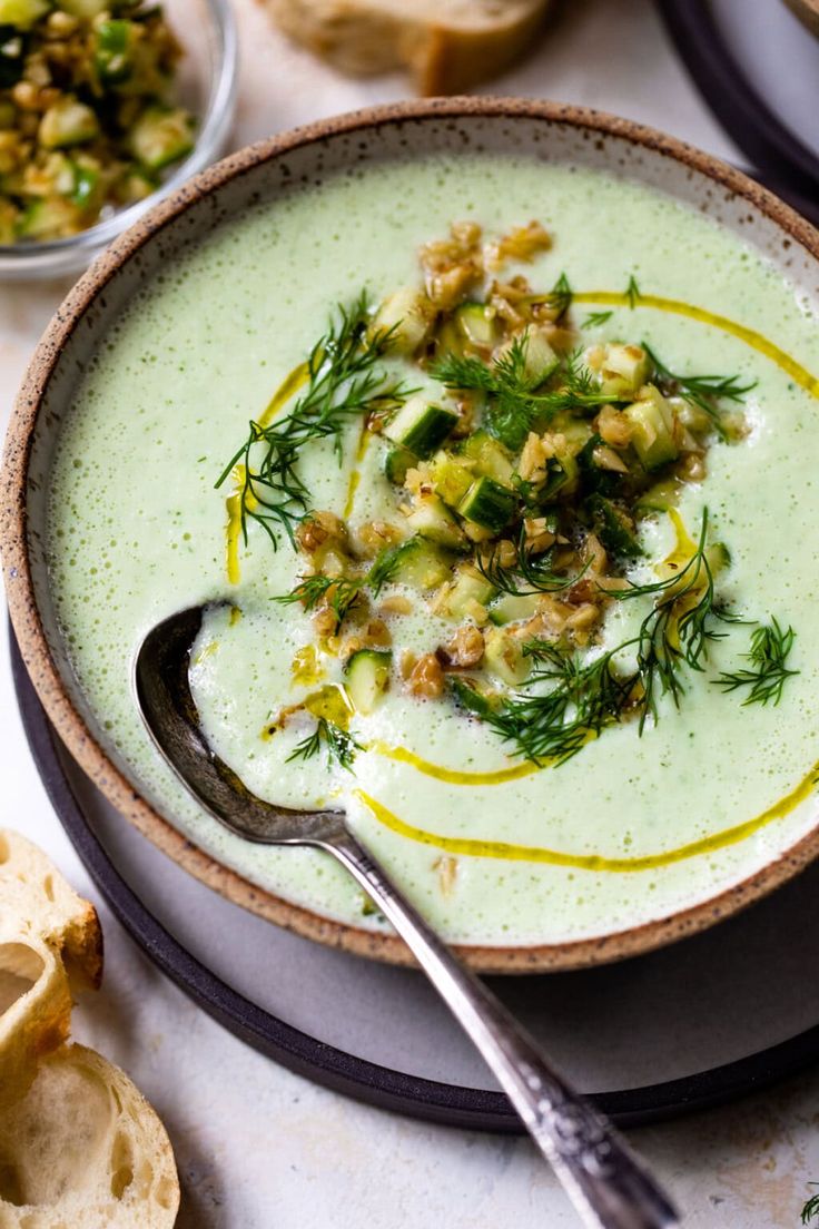 a bowl filled with soup and topped with green garnish next to slices of bread