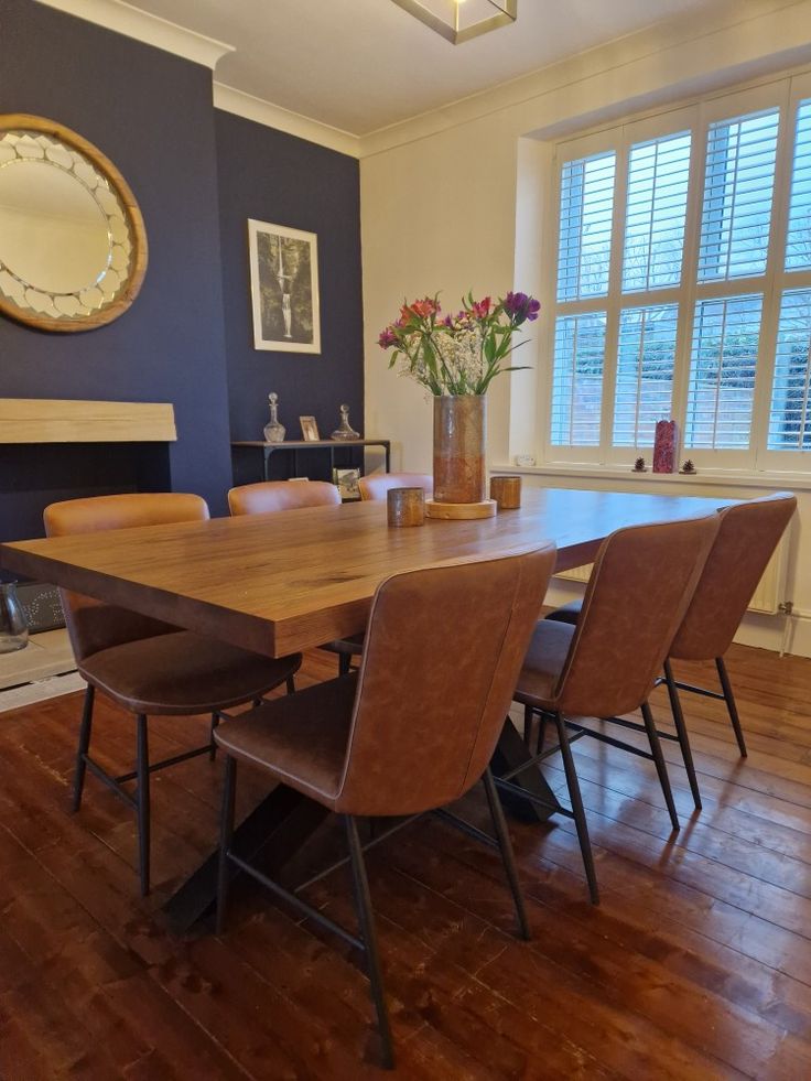 a dining room table with six chairs and a clock on the wall in front of it