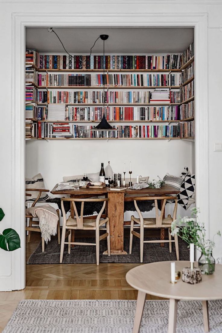 a dining room table surrounded by bookshelves and chairs