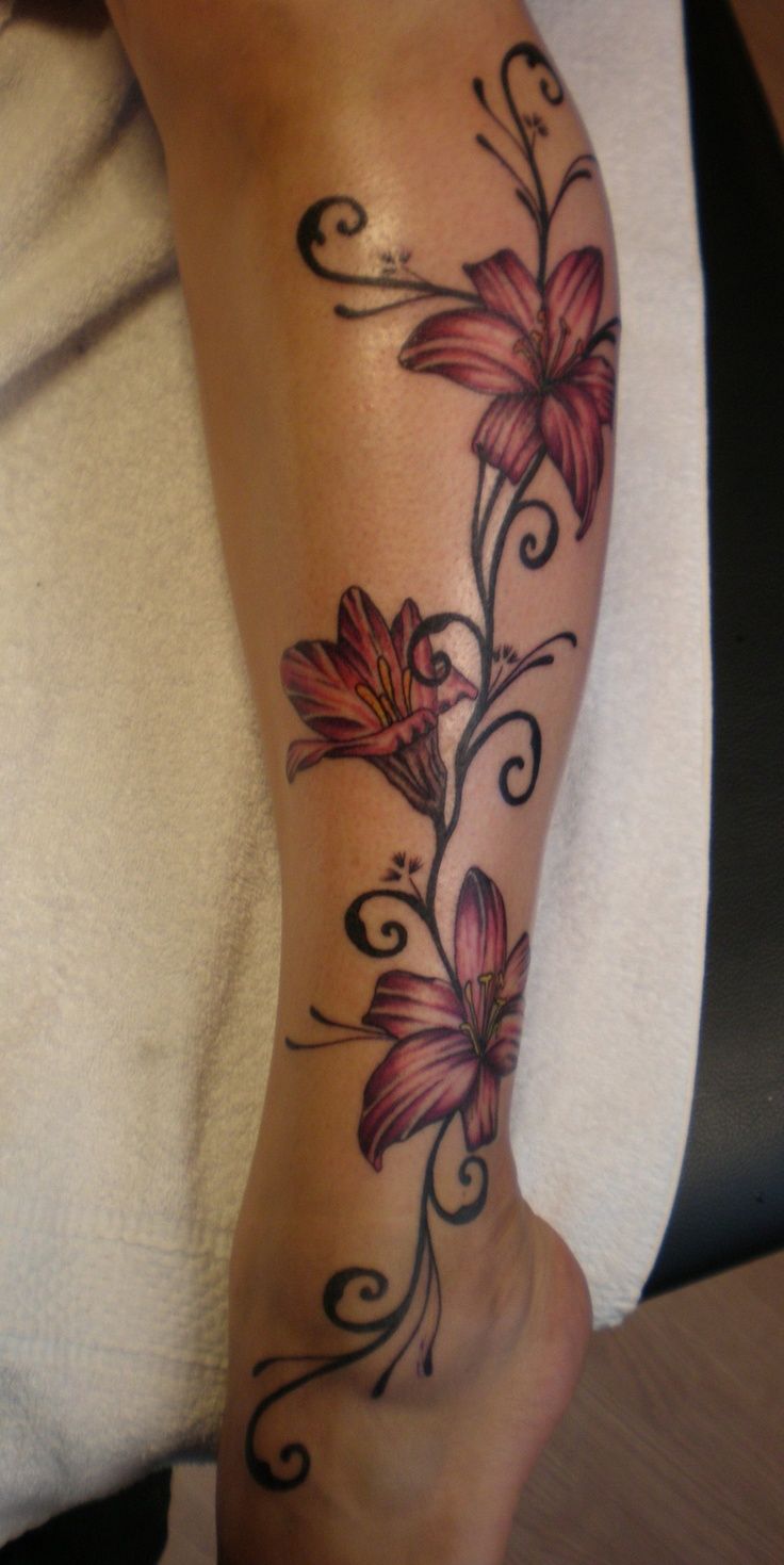 a woman's arm with flowers and swirls tattooed on the side of her leg