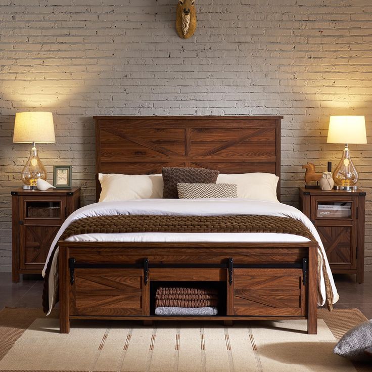 a bed with drawers underneath it in a room next to two lamps and a brick wall