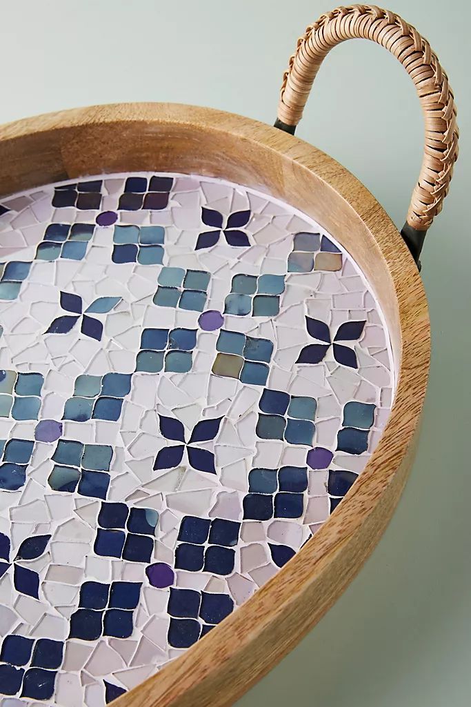 a wooden tray with blue and white mosaic tiles on the bottom is holding a wicker basket