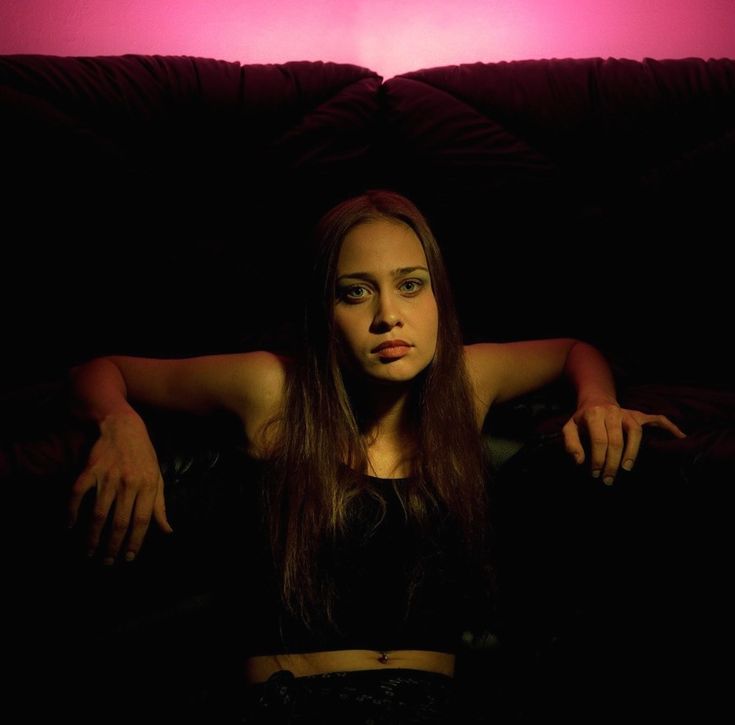 a woman sitting on top of a couch in the dark with her arms behind her head