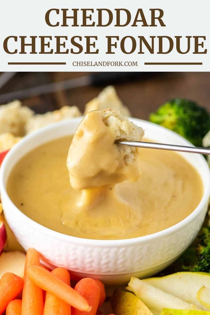 a bowl of cheese fondue with carrots, celery and broccoli