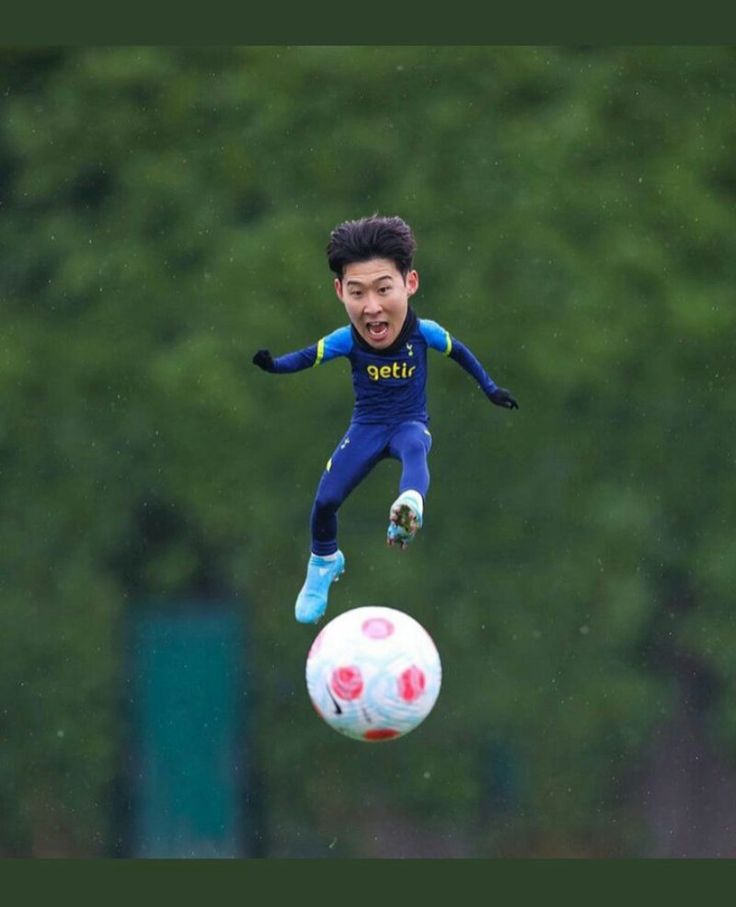 a young man is jumping in the air to kick a soccer ball