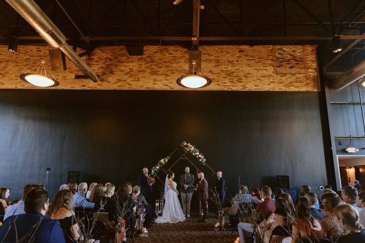 a couple getting married in front of an audience at a wedding ceremony with candles lit