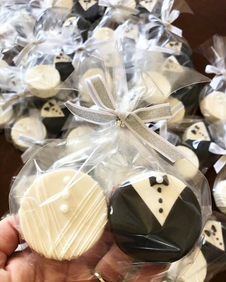 a person holding some cookies in their hand with bow ties and tuxedo on them