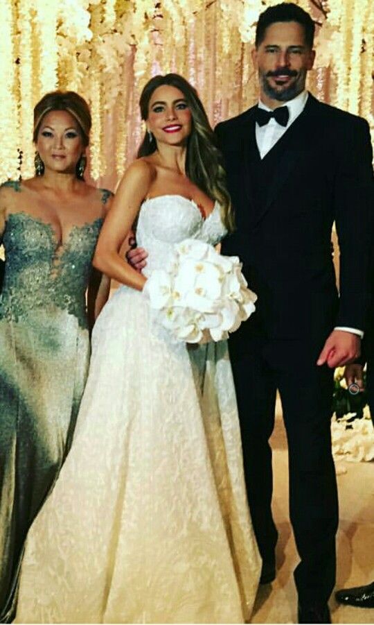 two women and a man standing next to each other in front of a wedding backdrop