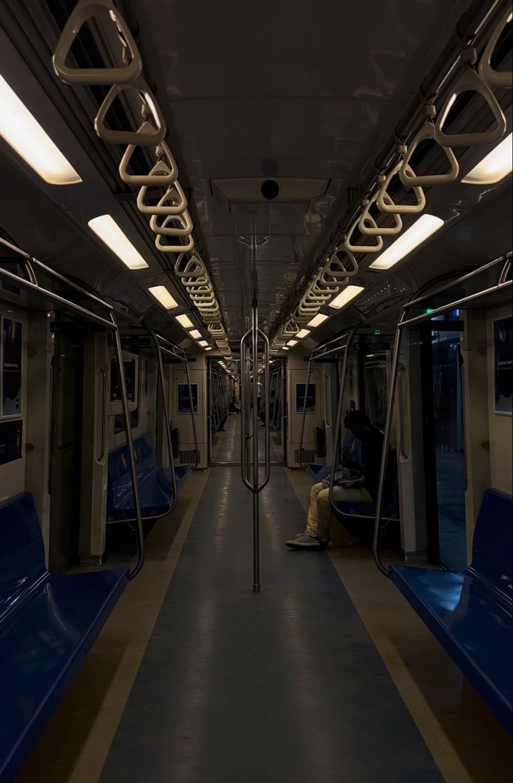 the inside of a subway car with blue seats and lights on each side of the train