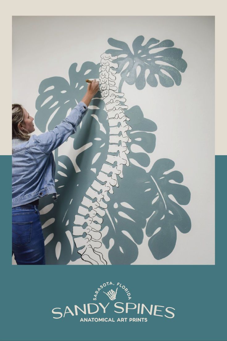 Dr. Sandy painting an anatomical skeleton with teal monstera leaves in the background on a wall of her office. Physiotherapy Room, Human Body Science Projects, Psychology Office Decor, Chiropractic Office Design, Massage Room Design, Clinic Art, Dream Home Gym, Gate City, Studio Pilates