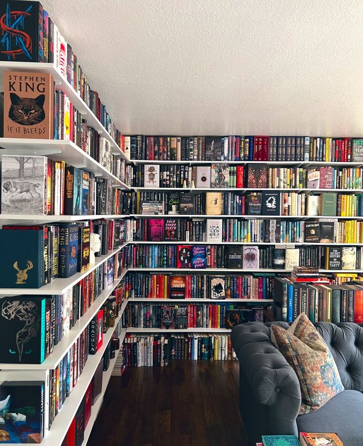 a living room filled with lots of books on top of white shelving unit units