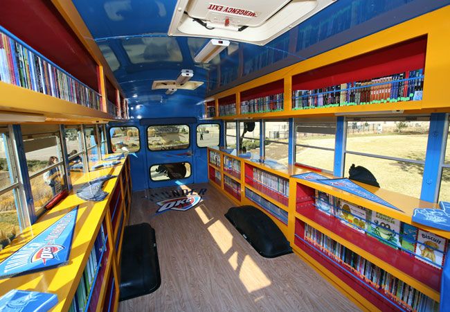 the interior of a brightly colored bus with bookshelves