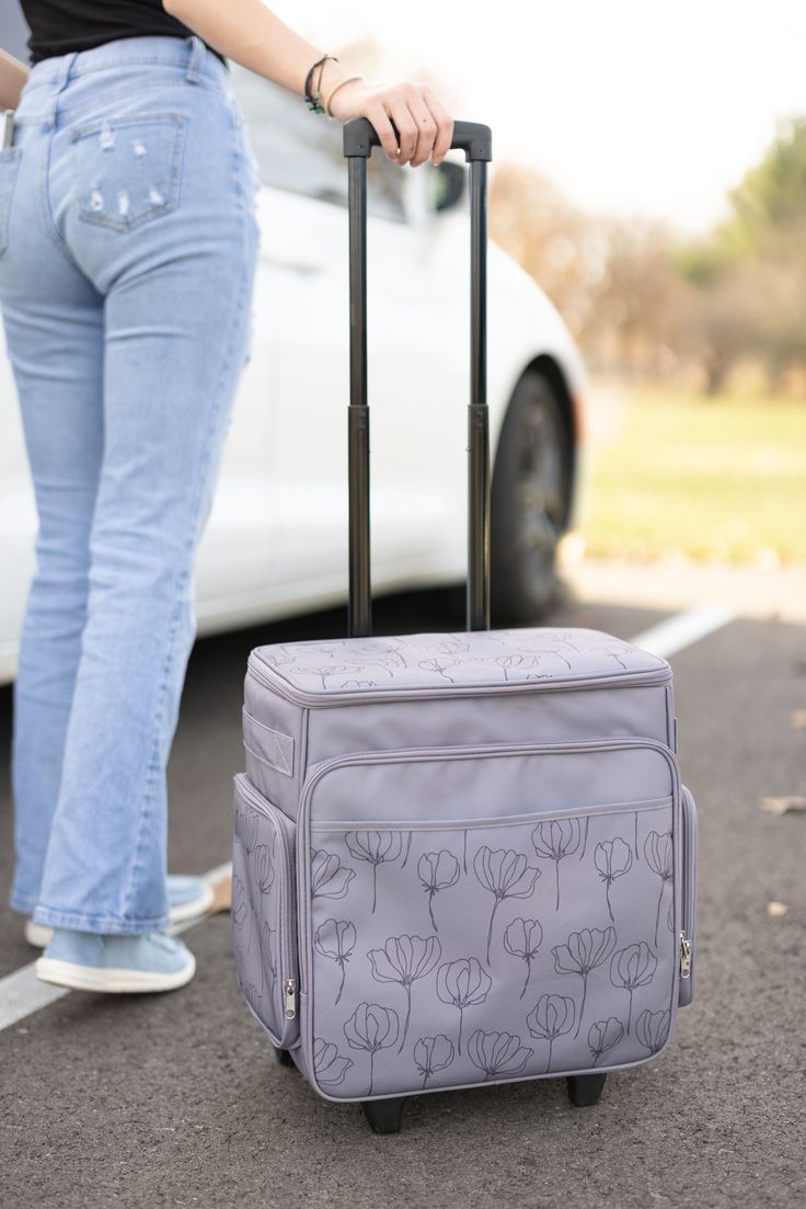 a woman standing next to a white car pulling a suitcase