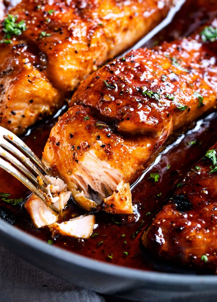 the chicken is being cooked with a fork in it's skillet and garnished with parsley