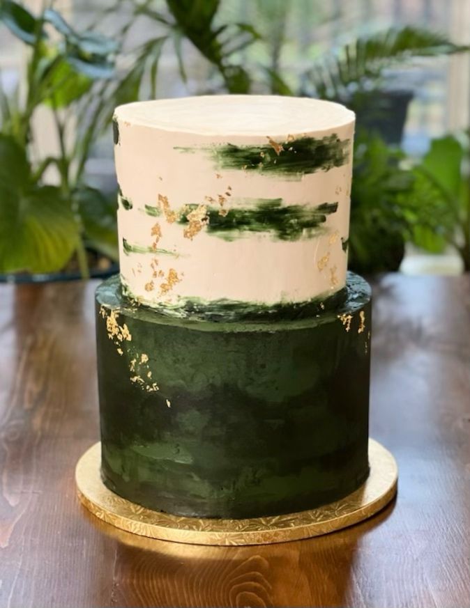 a green and white cake sitting on top of a wooden table next to potted plants