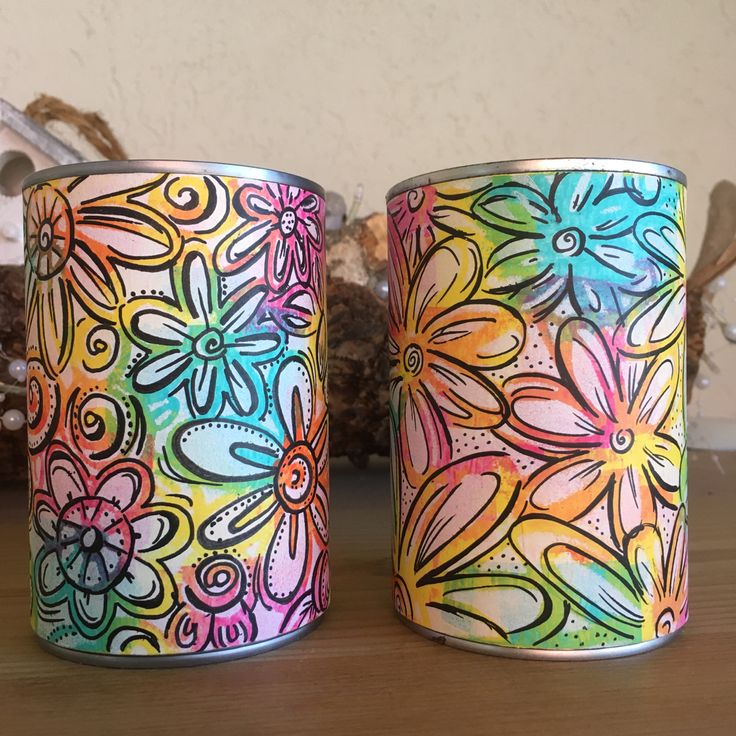 two colorful tin cans sitting on top of a wooden table