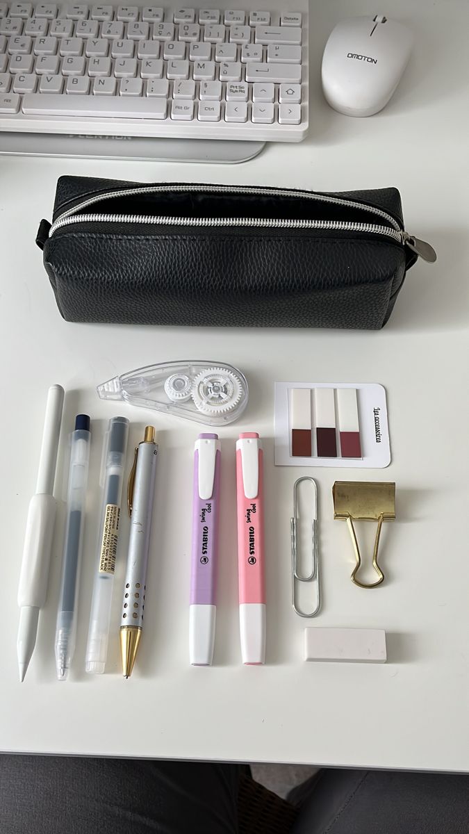 a white desk with pens, pencils and other items on it next to a keyboard