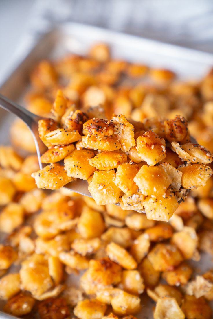 a spoon full of some kind of food on top of a pan filled with tater tots