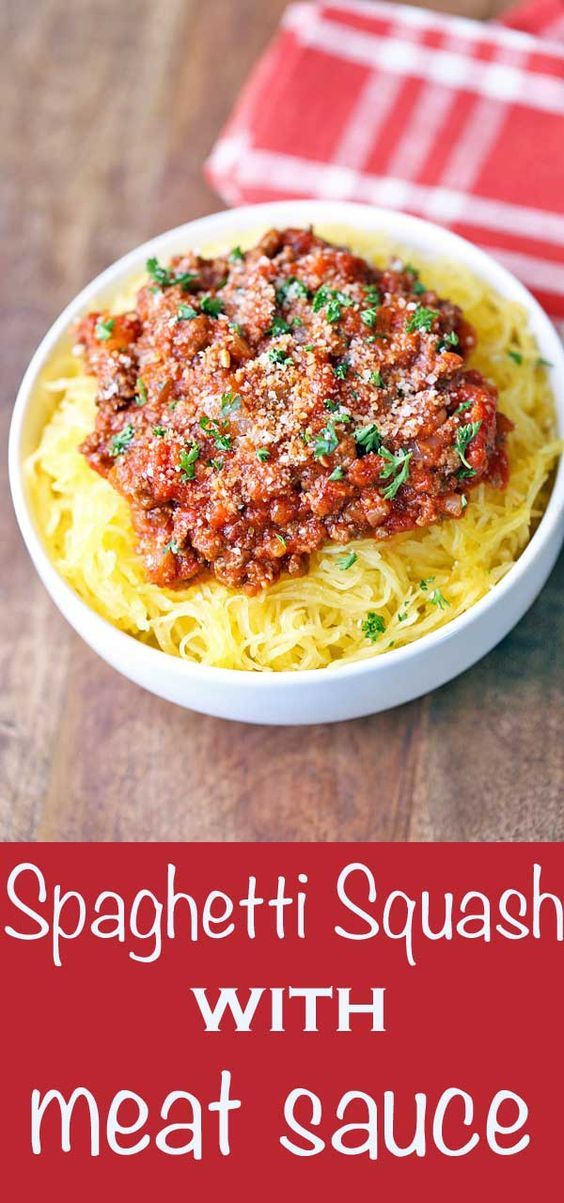 spaghetti with meat sauce in a white bowl on top of a wooden table next to a red napkin