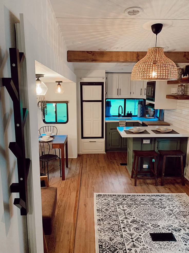 an open kitchen and dining room with wood floors, white walls and ceiling beams is seen from the doorway