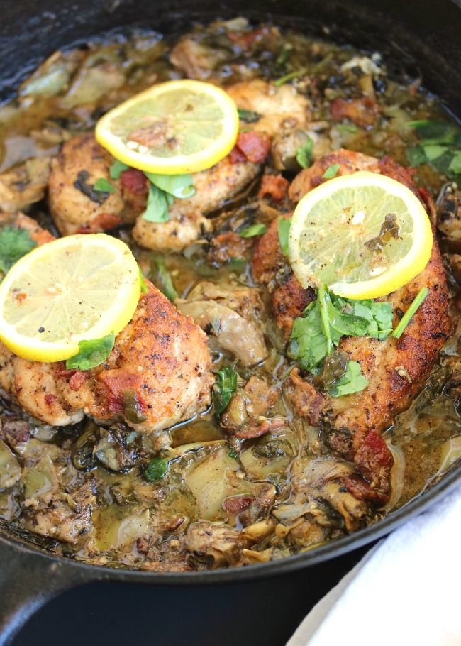 chicken with lemons and herbs cooking in a skillet on the stove, ready to be eaten