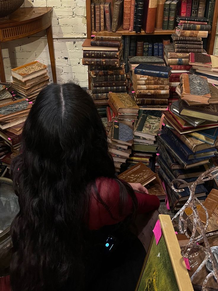 a woman sitting in front of a pile of books