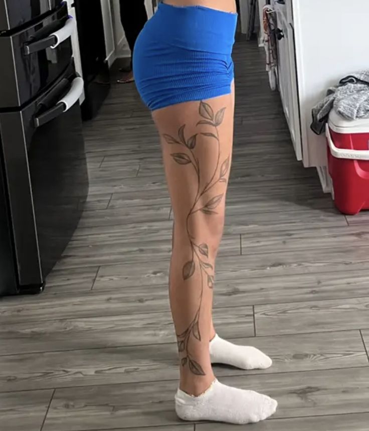 a woman is standing in the kitchen with tattoos on her legs and leggings