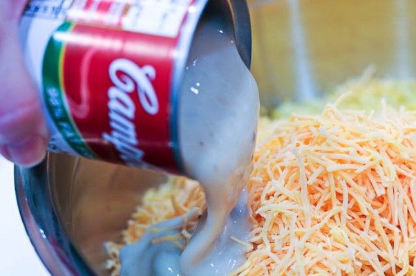 someone is adding shredded cheese to the food in a blender with a can of soda