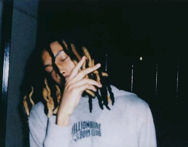 a young man with dreadlocks on his face and hands in front of him