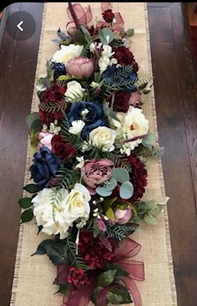 the table runner is decorated with flowers and greenery on burlap linens