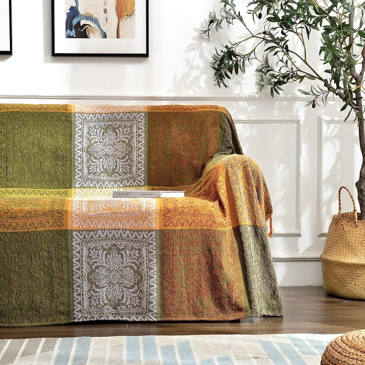 a living room with a couch covered in a blanket and potted plant next to it