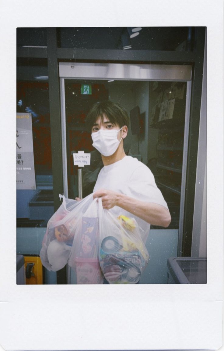 a man wearing a face mask and holding plastic bags