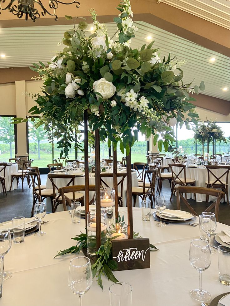 an elegant centerpiece with flowers and greenery is displayed in the middle of a banquet hall