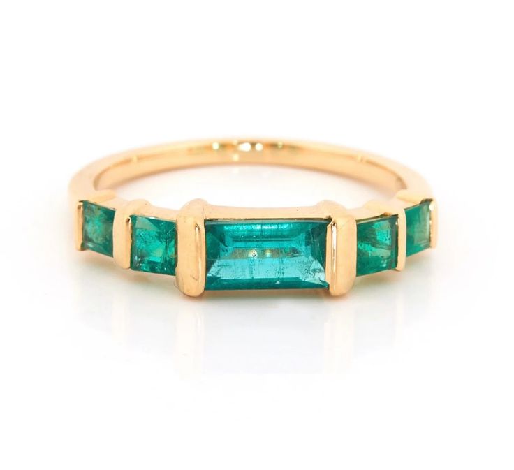 a gold ring with three emerald stones