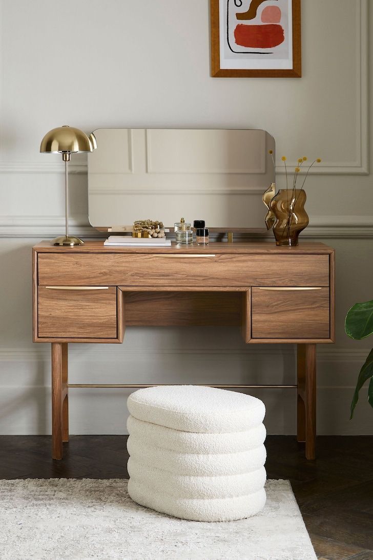 a wooden desk with a mirror and stool on it in front of a white rug