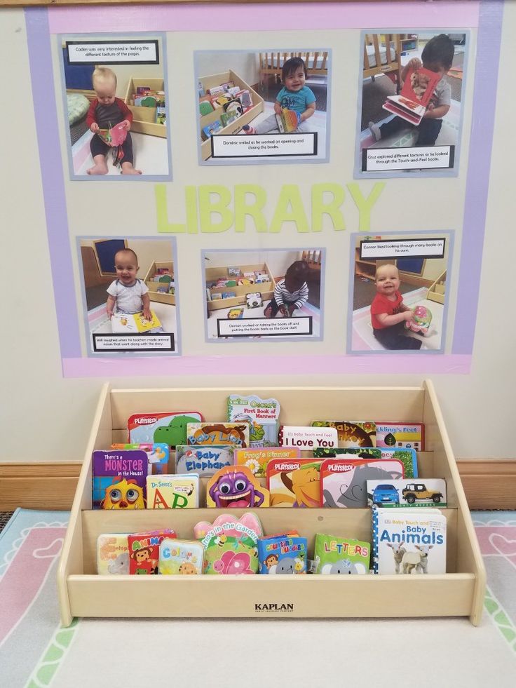 a book shelf filled with children's books in front of a library sign and pictures on the wall