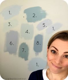 a woman standing in front of a white wall with blue paint on it and numbers