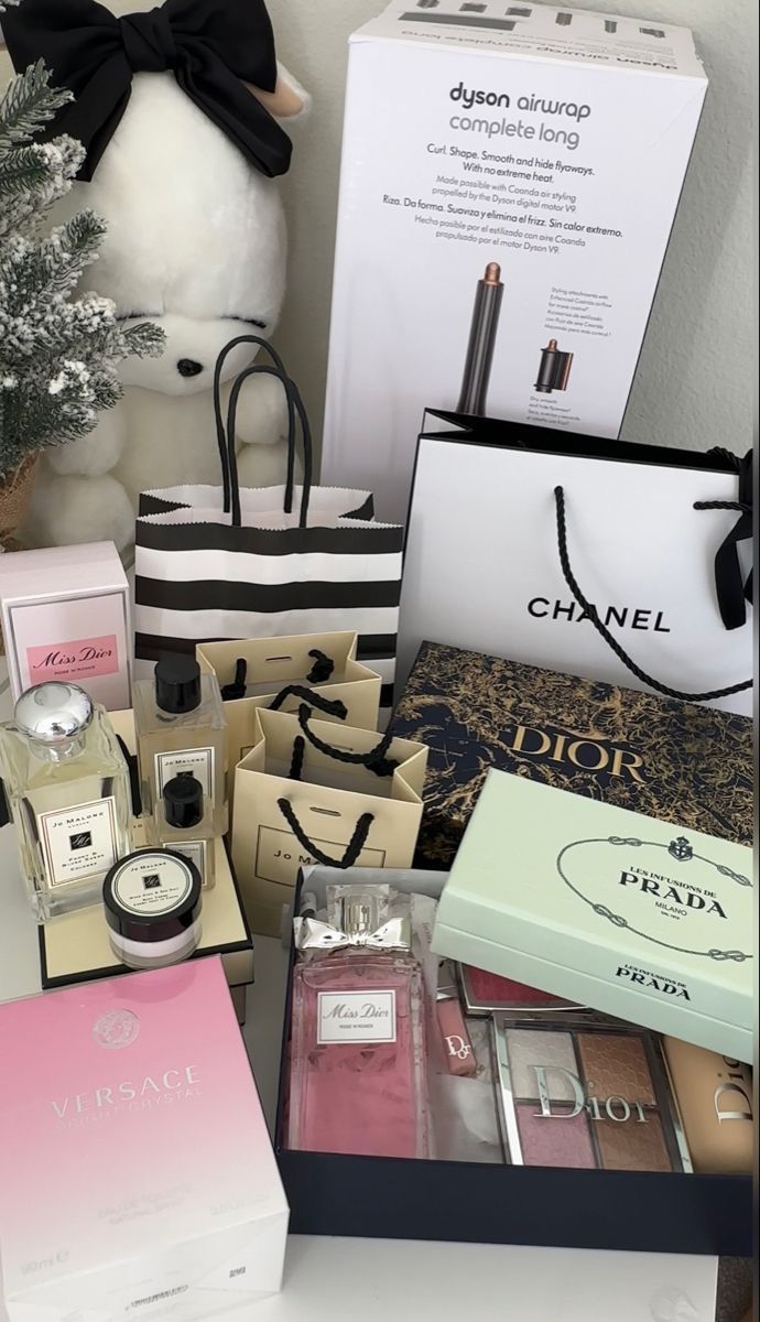 an assortment of beauty products displayed in front of a white teddy bear and christmas tree