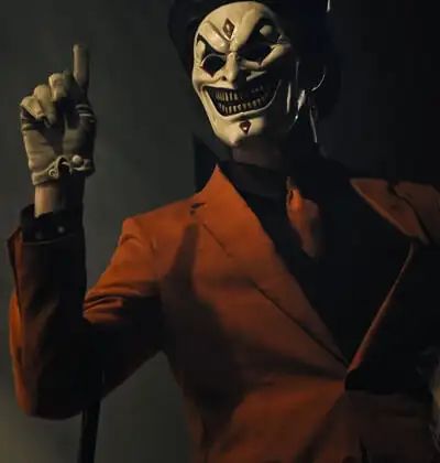 a man in a clown mask holding a baseball bat and pointing to the side with both hands