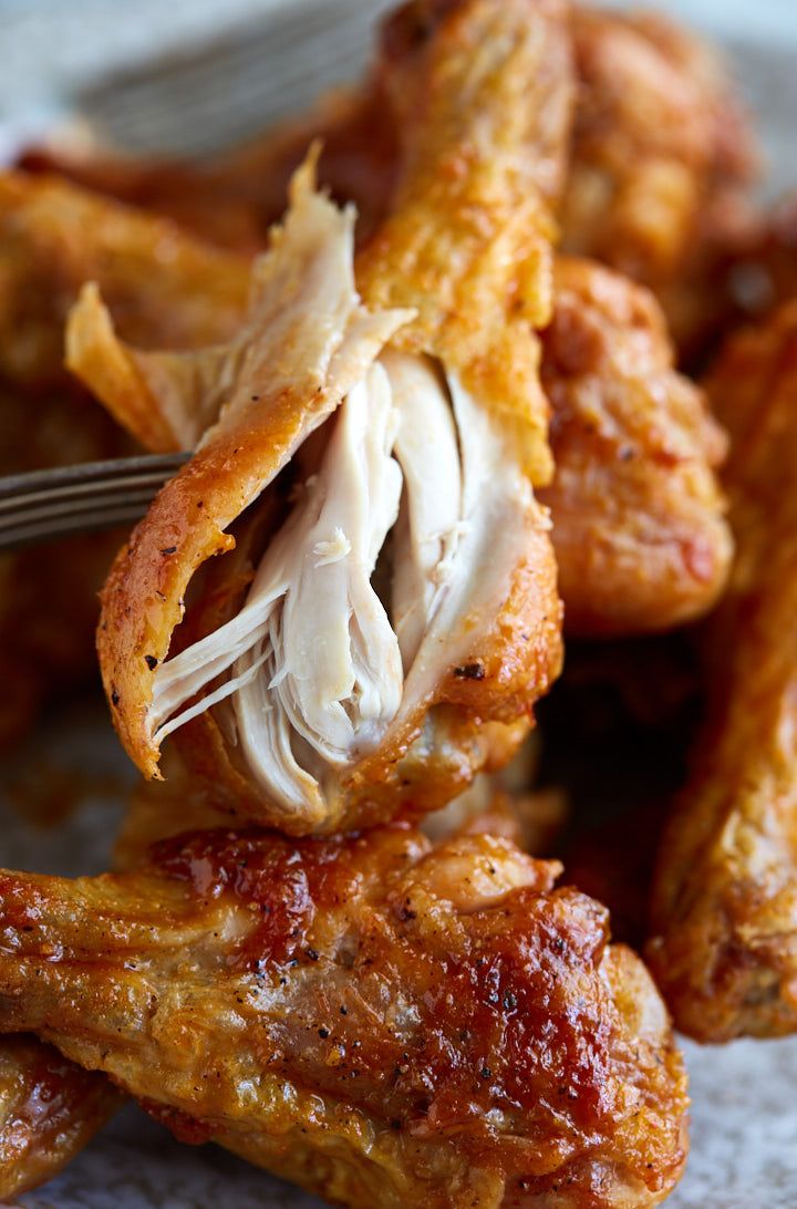 chicken wings are being held by a fork