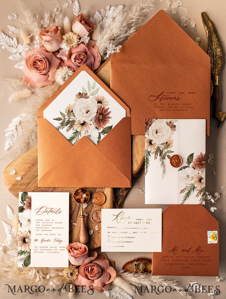 the wedding stationery is laid out on top of an envelope with flowers and foliage