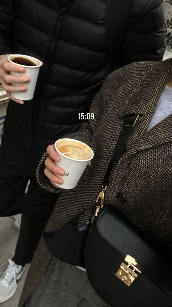 a man holding a cup of coffee in his hand while standing next to a backpack