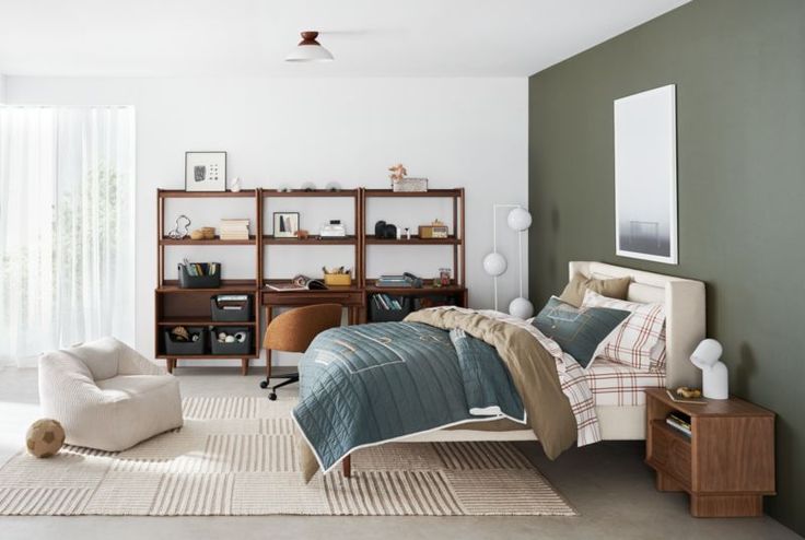 a bed room with a neatly made bed next to a chair and bookcases