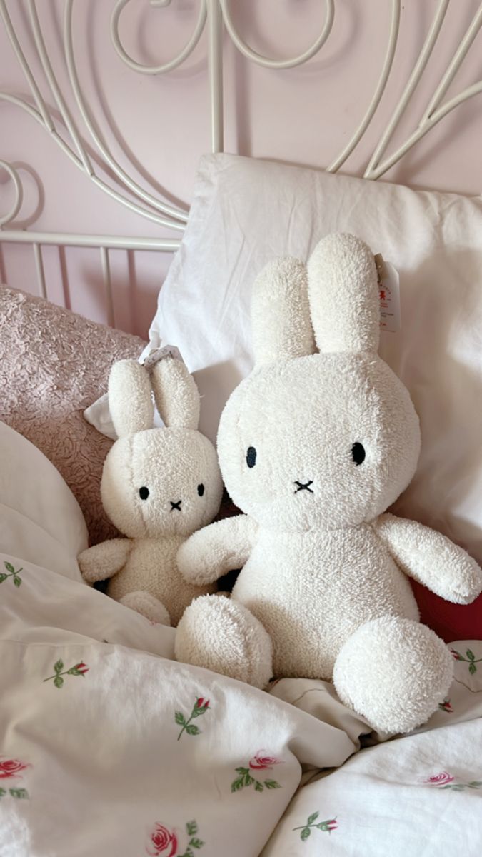 two white stuffed animals sitting on top of a bed